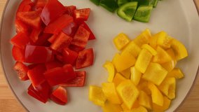 Closeup of chopped yellow, green and red bell peppers in a plate rotating top view. - Powered by Shutterstock - Get 15% off with code: PIKWIZARD15