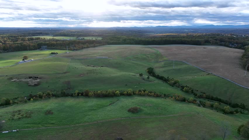 Rural hilly landscape in America during cloudy day in fall. Aerial backwards wide shot. Villa and mansion with private driveway and cul-de-sac. Panorama view of nature.
