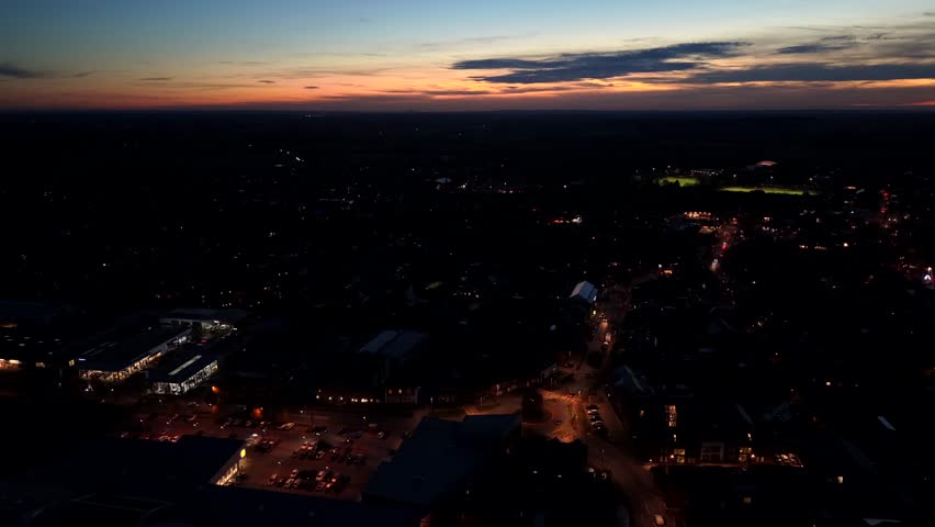 Traffic on warm glowing street and roundabout at twilight. Aerial flyover wide shot. Sunset time in american town with cars on orange streets Housing area and neighborhood at dusk.