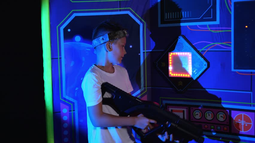 Close-up of children playing laser tag, they run up and touch an electrical appliance and charge their weapons with energy. The process of playing laser tag with laser weapons.