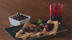 Close-up of homemade crepes topped with fresh huckleberries, berry jam, and powdered sugar on a rustic wooden table. - Powered by Shutterstock - Get 15% off with code: PIKWIZARD15