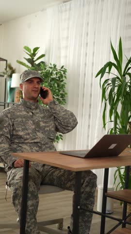 American soldier in camouflage uniform talking on the phone at home