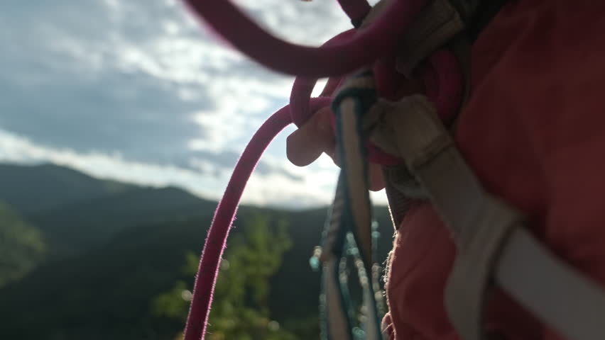 Climber tying figure eight knot to harness