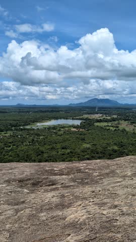 Caucasian woman standing at the peak of Pidurangala, enjoying the summit moment of success and adventure on an active trail journey in Sri Lanka, a confident female discovering the mountain top