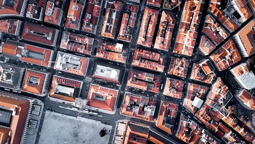 A detailed aerial captures Lisbon Baixa district with dense red rooftops and narrow grid-like streets