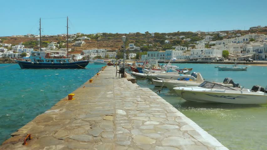 Scenic view of a historic port pier with calm waters, boats docked along the quay, and charming waterfront buildings capturing the essence of a coastal town.
