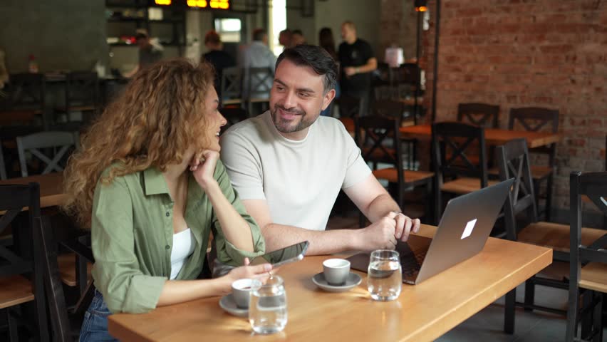 Romantic couple talking and working in a modern coffee shop