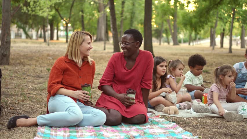 Diverse group of mothers and children picnicking in the park