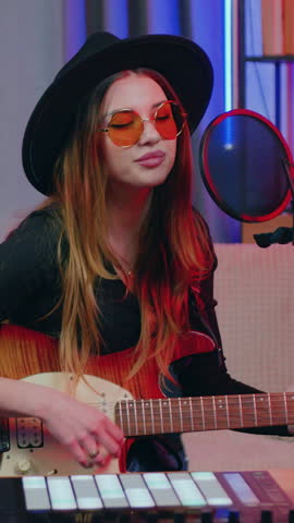 Portrait of woman in hat and glasses which recording songs in home studio in the evening