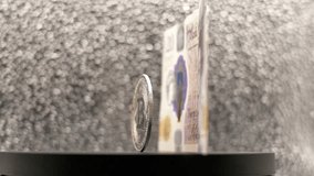 Twenty pound banknote next to a Bitcoin cryptocurrency coin spinning on a display stand - Powered by Shutterstock - Get 15% off with code: PIKWIZARD15