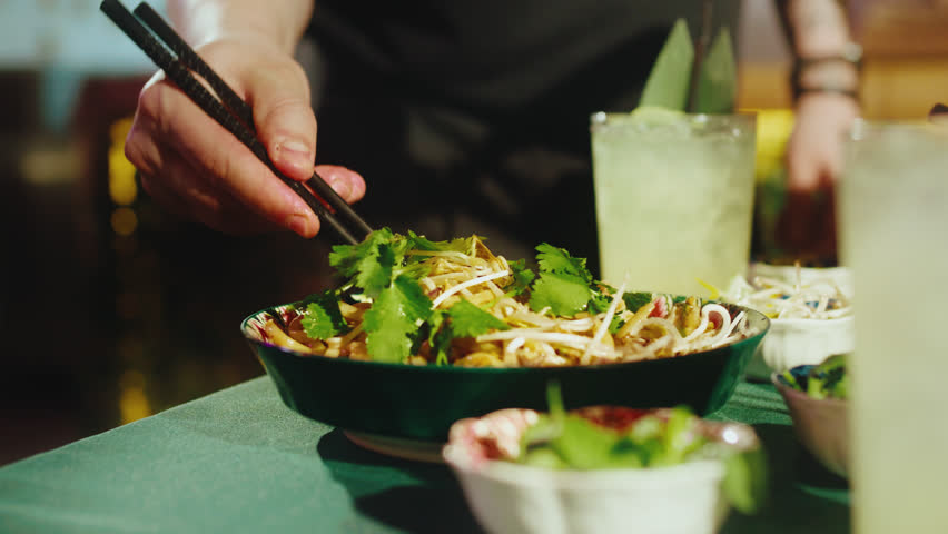 Eating Pad Thai Noodles with Shrimp Using Chopsticks in Restaurant