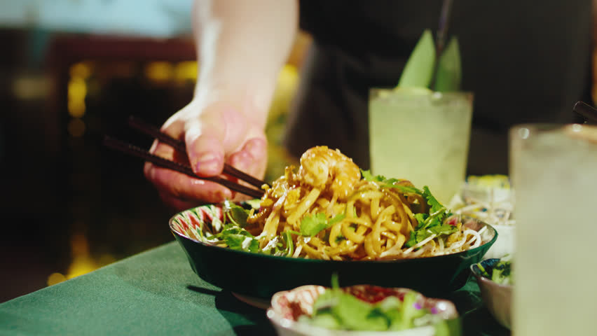 Eating Pad Thai Noodles with Shrimp Using Chopsticks in Restaurant