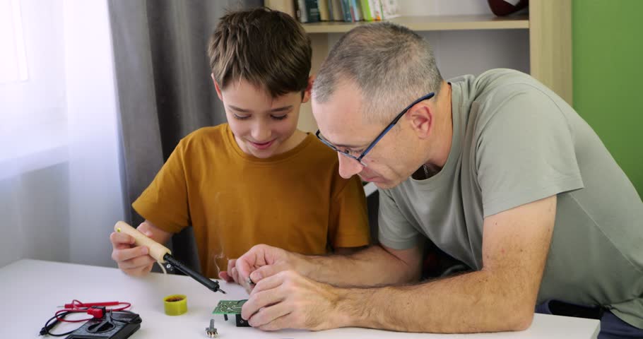 Family works on stem project at home. Father guides boy through electronics task. hands on learning and creative teamwork. Stem activity develops skills and supports steady interest in technology.