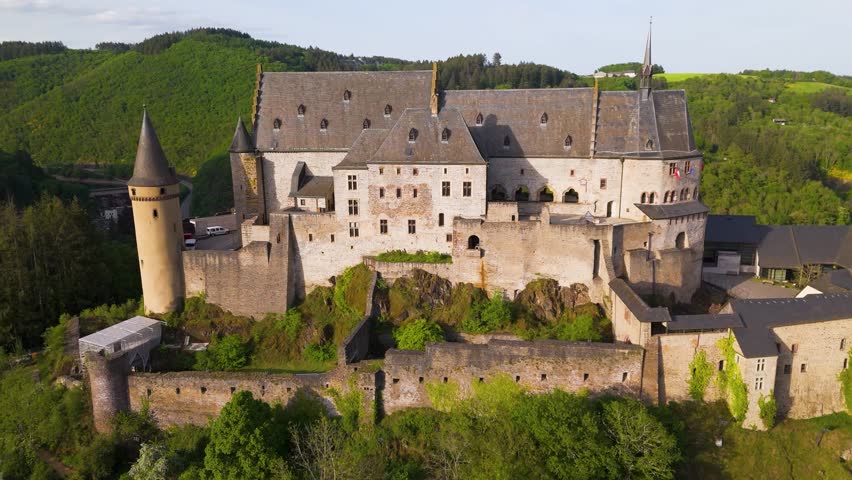 vianden castle chateau de historic domes walls architecture white cars parked upper area complement green hills to from left right afar circling drone luxembourg
