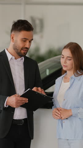 Car salesman discussing purchase contract with female customer