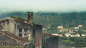Fast-moving clouds sweep across the hills, as birds fly over an old rooftop and chimney in the foreground. Cars and distant people appear in the background while fog drifts across the trees - Powered by Shutterstock - Get 15% off with code: PIKWIZARD15