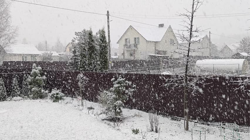 Winter returned in the middle of spring. It is snowing heavily with large snowflakes. Snow lies on the roofs of houses, branches of trees and on the ground. Abnormal weather with precipitation