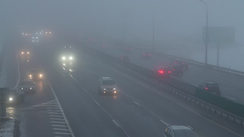 cars are moving along the highway in fog and poor visibility conditions