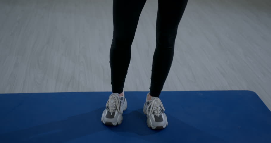 Fit woman lower body black sportswear pants posing indoors fitness studio empty room