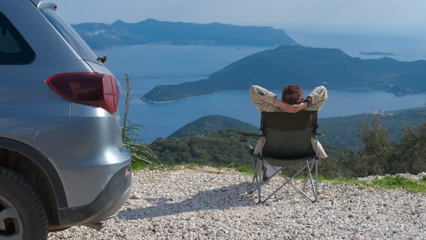 Tourist woman relaxing in folding chair, enjoying beautiful seascape view from mountain top, then folding and carrying the chair to her car