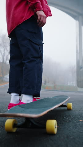 Rear view legs of an unrecognizable teenager on a skateboard. Skatewalk in the park, youth subculture and hobby concept.