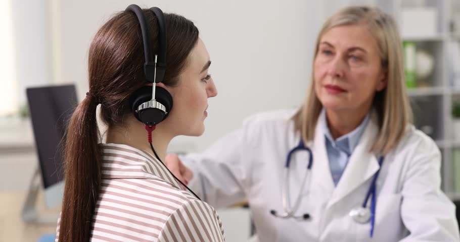 Hearing test. Doctor adjusting patient's audiometric headphones in clinic, selective focus