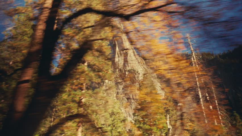 POV shot of a car driving through Yosemite Valley, showing towering granite cliffs and pine trees under a clear blue sky
