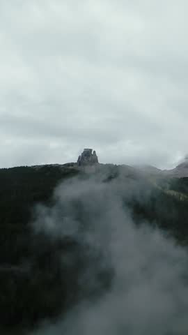 dolomites secluded stone fortress beneath cloudy skies, remote tower shrouded by mountain mists and swirling clouds, ancient fortress concealed among mountain mists under swirling cloudy sky