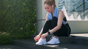 Young woman athlete preparing for challenging exercise, tying white shoelaces, enjoying fitness lifestyle outdoors in city setting, ready for sport workout, wearing earphones and smartwatch. - Powered by Shutterstock - Get 15% off with code: PIKWIZARD15