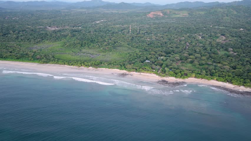 Beautiful aerial view of avellanas beach in guanacaste, costa rica, showing the sandy shore, blue ocean waters, and dense tropical jungle