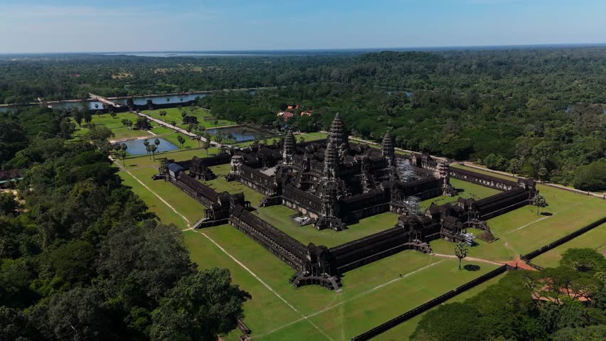 An ascending pull-back aerial shot reveals Angkor Wat and its surrounding landscape, showcasing the temple’s full layout and forested setting