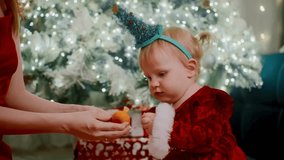 child investigates present, young child examines festive gift, toddler explores wrapped present near christmas tree, little child reaches for orange in holiday wrapped - Powered by Shutterstock - Get 15% off with code: PIKWIZARD15