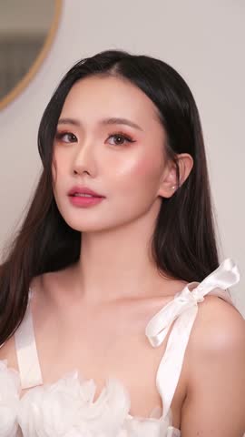 Close-up of a woman applying makeup to her face, showcasing a step-by-step makeup routine. The video highlights the process of foundation, brush eyeshadow, mascara, and lipstick