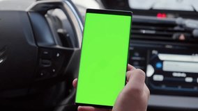 Close-up of a driver’s hand using a smartphone with a green screen inside a car, showing mobile technology, driving, and digital device usage. - Powered by Shutterstock - Get 15% off with code: PIKWIZARD15