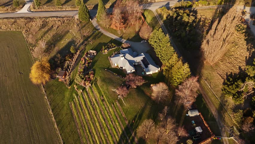 Aerial top down of countryside villa with solar panels and private vineyards in Wanaka, New Zealand. Colored trees in fall season. Luxury buildings in NZ.