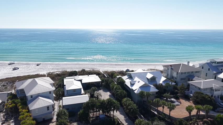 Amazing drone fly over white coastal houses overlooking the bright turquoise Gulf of Mexico on a sunny day, 30A, Florida, USA