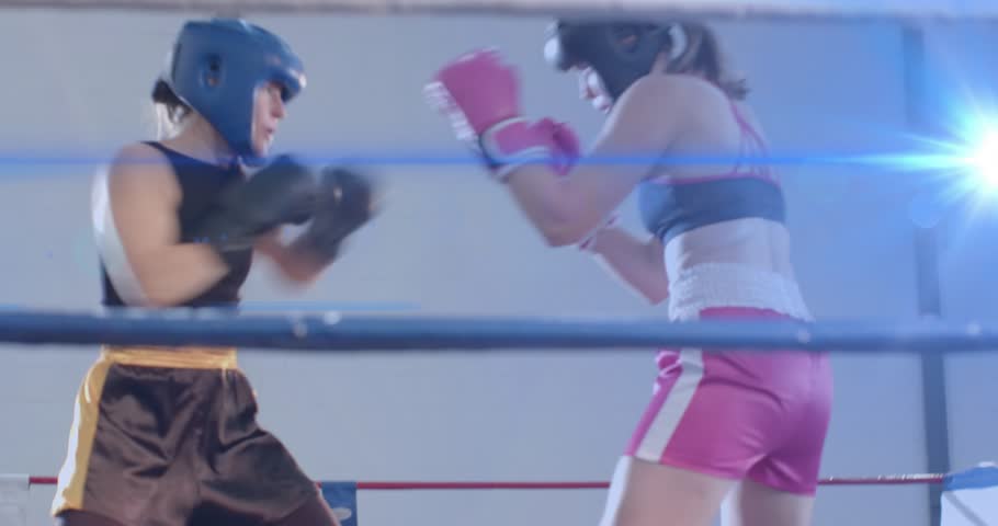 Right boxer pressing and jabbing, left boxer bending near ropes then regaining gloves for health. Sparring, ring, headgear, athletes, competition, motion, focus