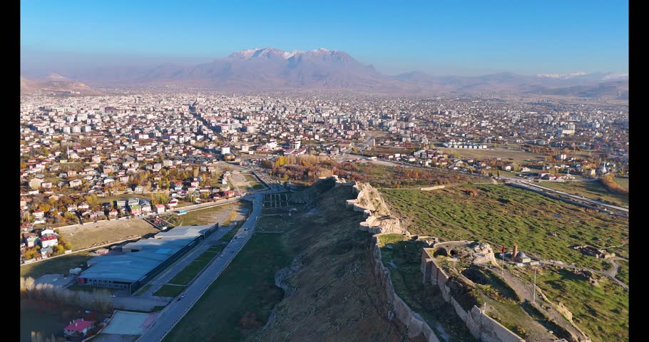 Cinematic 4K drone footage capturing the vast, ancient fortress of Van Castle (Van Kalesi) and its massive stone walls, overlooking the modern city and surrounding plains under a clear sky.