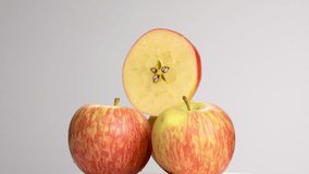 Stack of fresh Royal Gala apples rotating on black background. Three whole fruits with a half-cut slice on top showing star-shaped core and seeds. - Powered by Shutterstock - Get 15% off with code: PIKWIZARD15