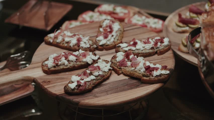 Rustic bruschetta topped with cheese and cured ham on buffet table