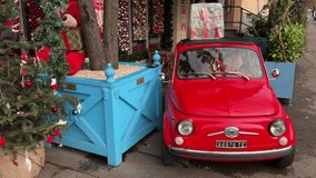 Bright red vintage car parked among colorful christmas decor - Powered by Shutterstock - Get 15% off with code: PIKWIZARD15