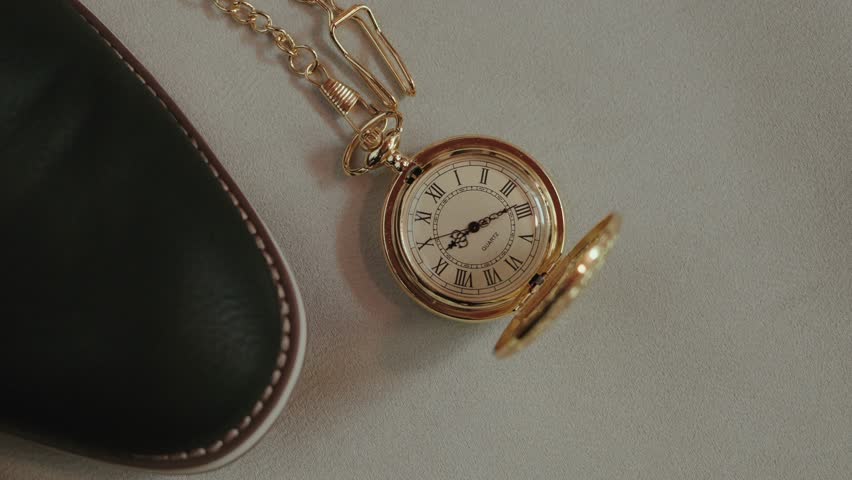 vintage gold pocket watch resting beside leather shoe