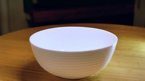 Slow motion popcorn pouring into white bowl on wooden table some kernels spilling during movie night preparation cozy cinema snack - Powered by Shutterstock - Get 15% off with code: PIKWIZARD15