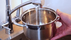 Slow motion water pouring from kitchen faucet into metal pot held by hand cooking preparation home kitchen meal making process - Powered by Shutterstock - Get 15% off with code: PIKWIZARD15