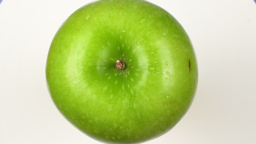 Top-down view of a fresh wet Green Apple (Granny Smith) rotating on white background. Healthy fruit with water droplets isolated.