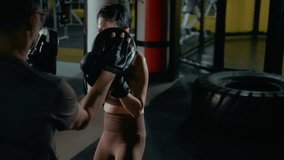 Japanese woman boxing with a coach holding pads, demonstrating clean technique and professional focus during an intense training session in the gym. - Powered by Shutterstock - Get 15% off with code: PIKWIZARD15