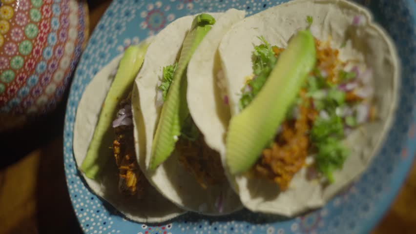 Close-up of three tacos with avocado on a plate. Mexican food concept