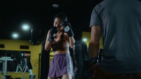 A Japanese woman trains in kickboxing at the gym, striking the coach’s pad with a powerful kick, demonstrating discipline, focus, and strong control during sparring practice. - Powered by Shutterstock - Get 15% off with code: PIKWIZARD15