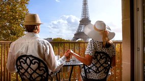 Rear view of a romantic couple holding hands on a balcony and enjoying the view to the Eiffel Tower in Paris, France - Powered by Shutterstock - Get 15% off with code: PIKWIZARD15