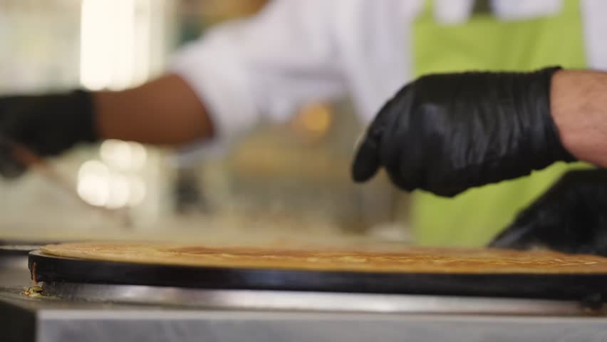 Close up view in slow motion of A Chef flipping a crepe in a restaurant in Paris